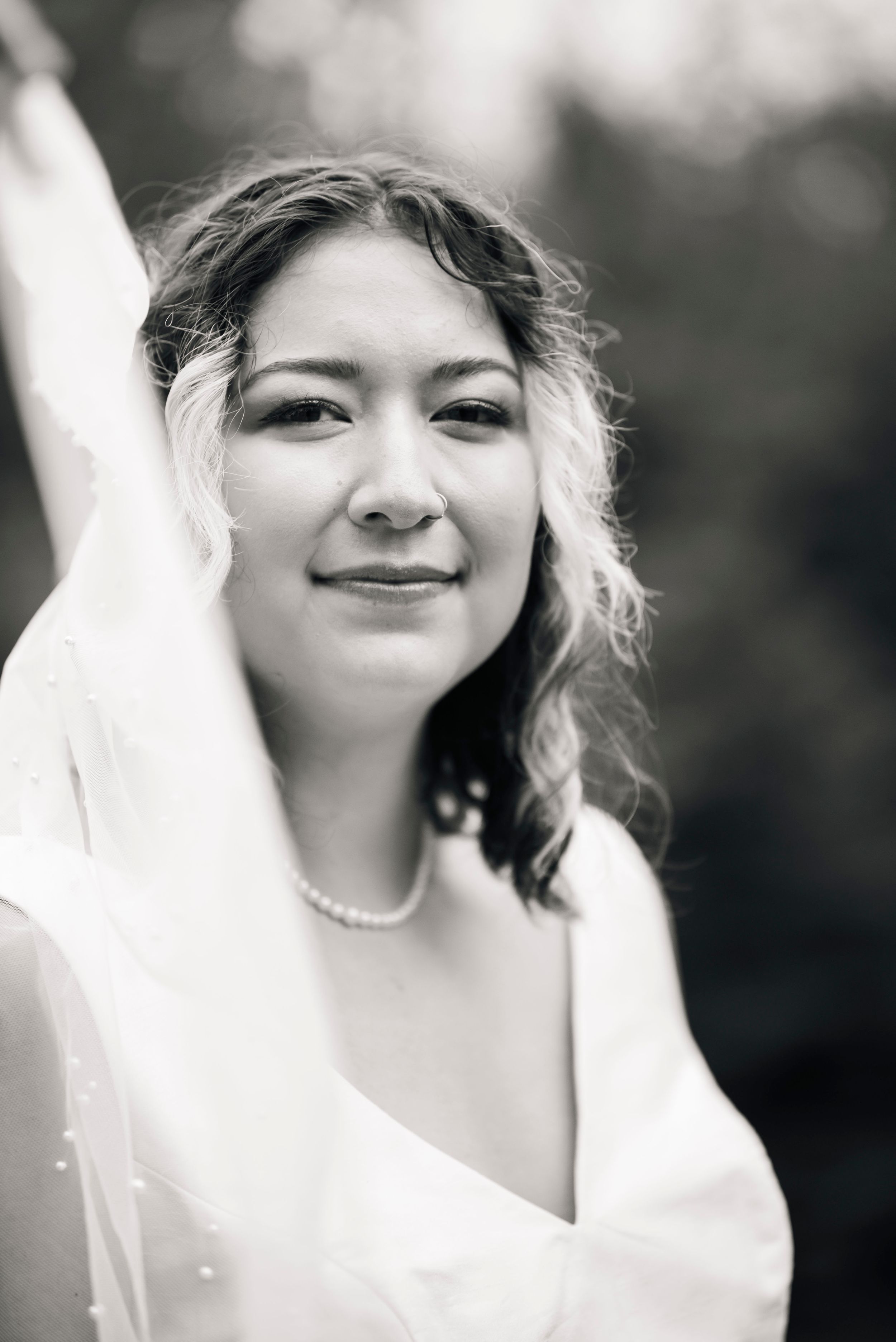 An elegant bridal portrait in black and white showcasing pearls and a delicate veil.