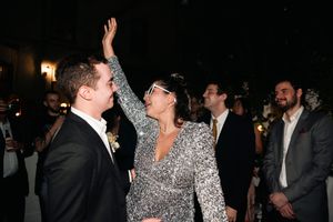 A couple embraces while dancing at a formal evening event, with the person in a sparkly dress shimmering under the lights.