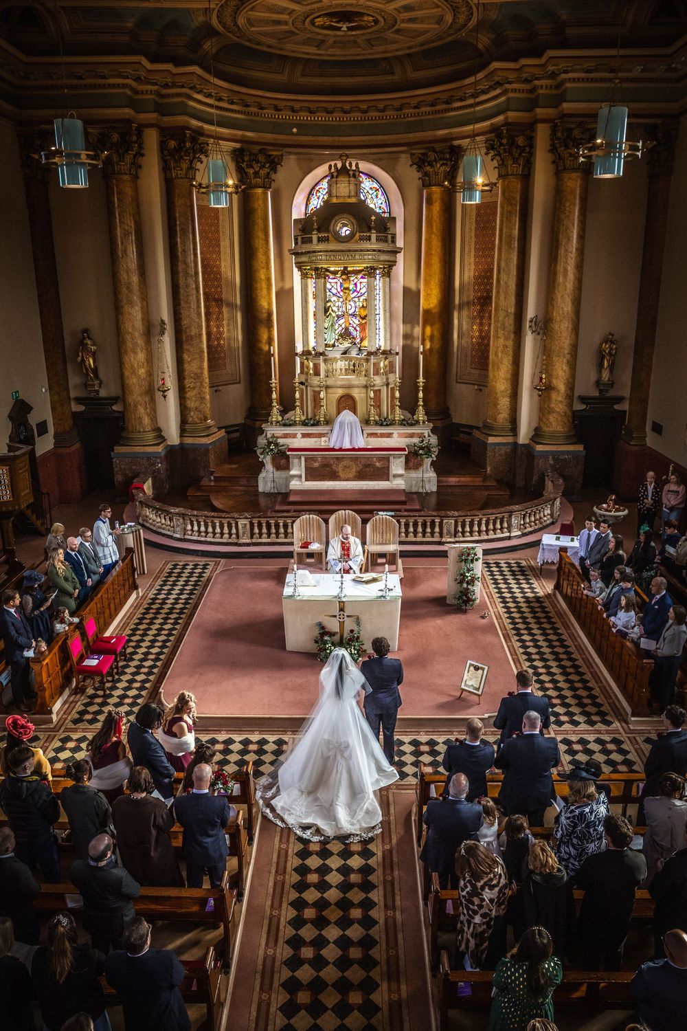 Elegant church wedding ceremony with bride and groom at the altar, guests seated in ornate pews of a grand cathedral.