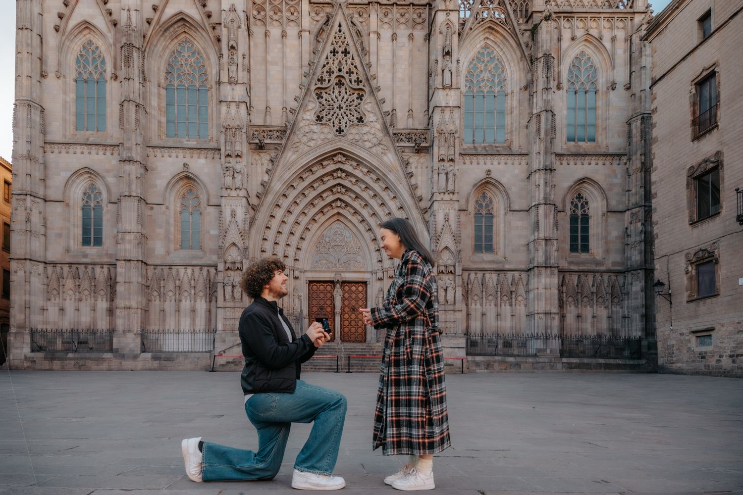 A romantic morning surprise proposal under a historic stone archway in the quiet streets of the Gothic Quarter, Barcelona.