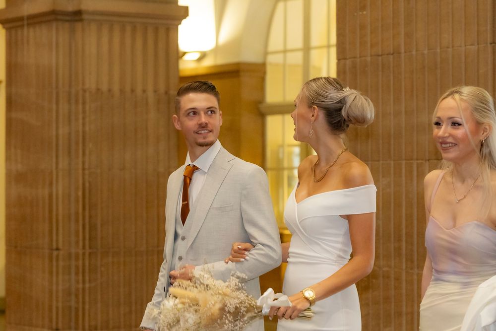 Wedding party members posing in an elegant hallway with golden walls.