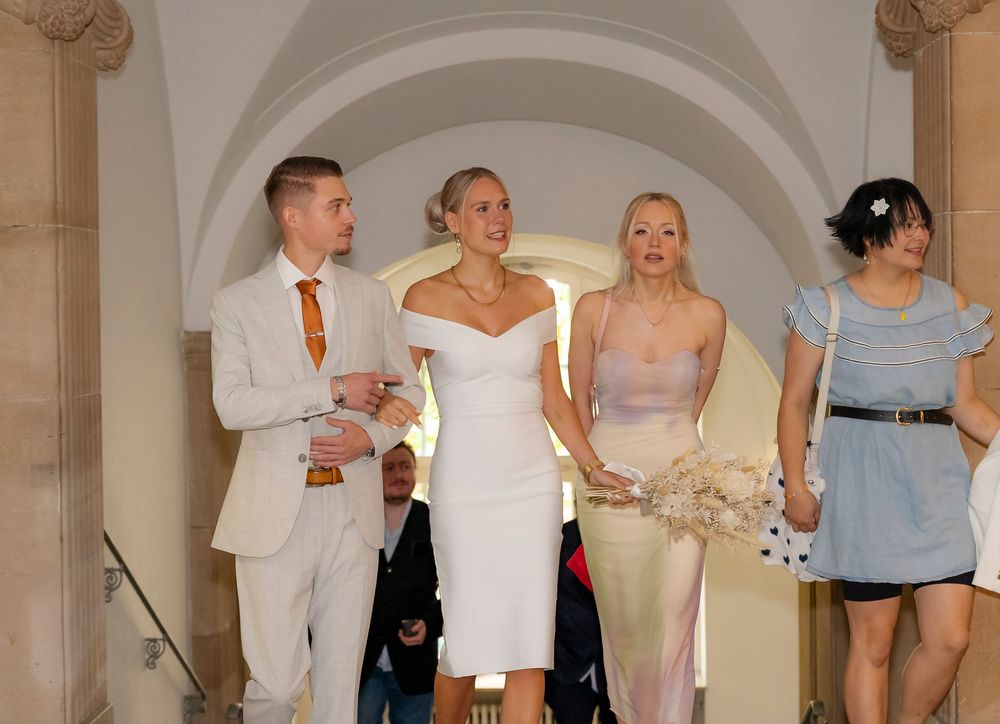 Wedding party members gathered in an elegant indoor space with arched ceilings.