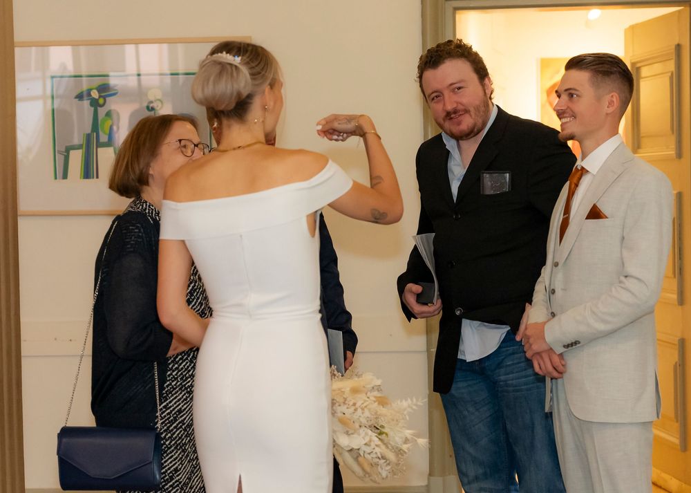 Wedding party members gathered in formal attire inside a warmly lit venue.