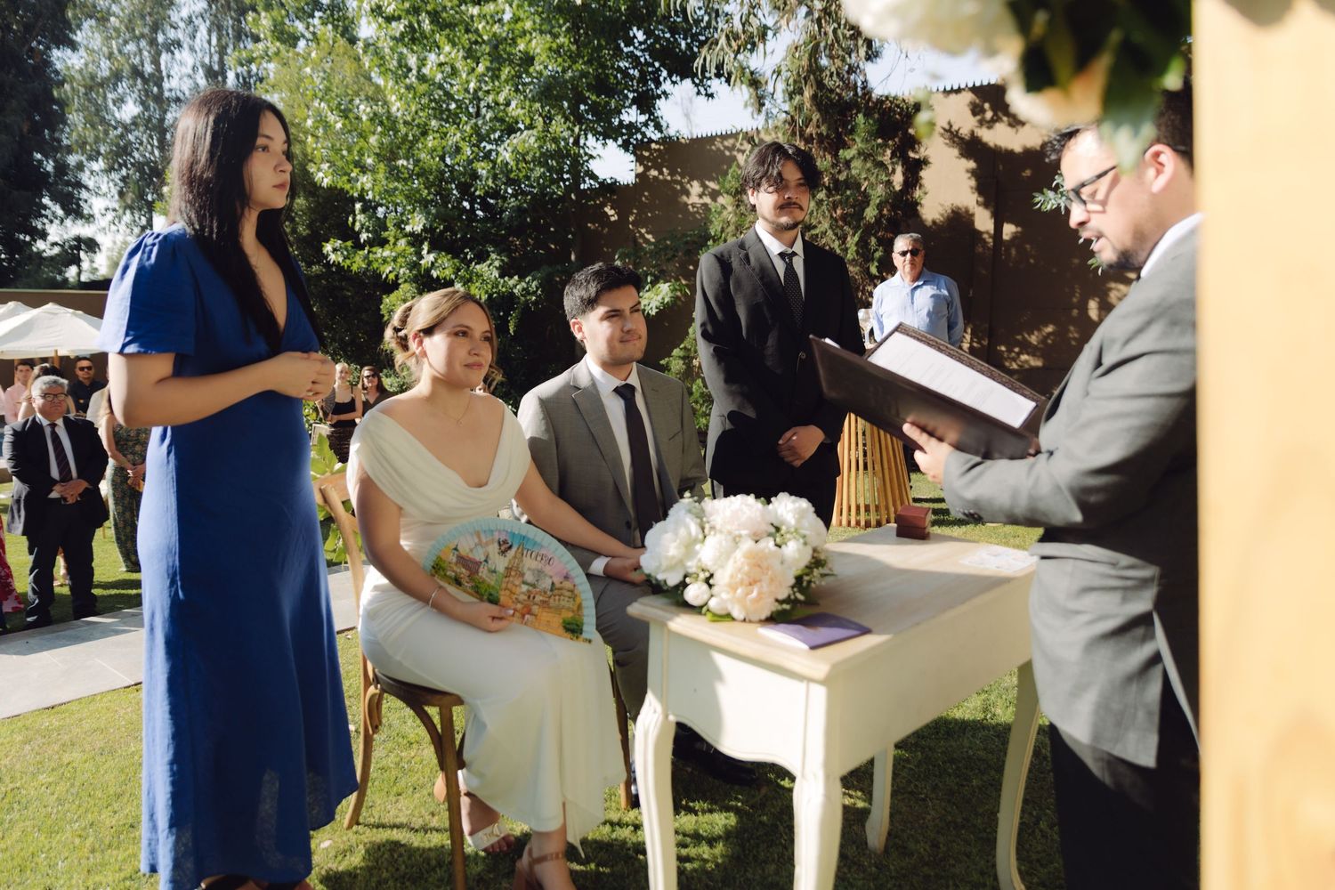 Officiant reading vows to bride and groom at elegant outdoor garden wedding ceremony.