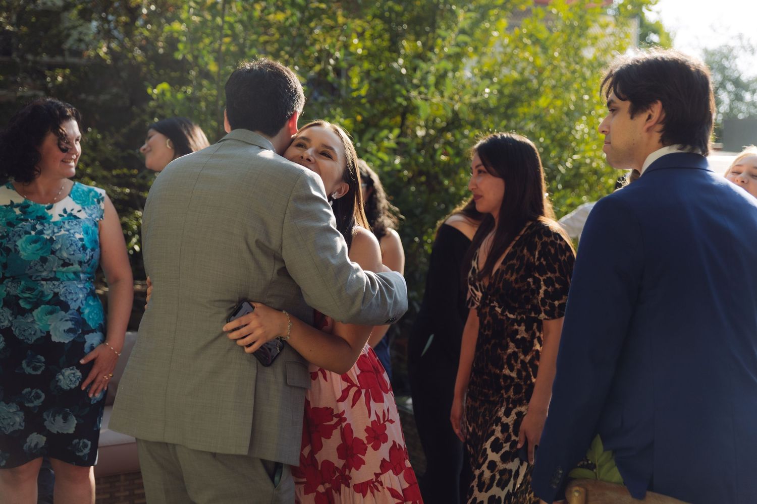 Guests embracing and chatting at an elegant outdoor wedding celebration.