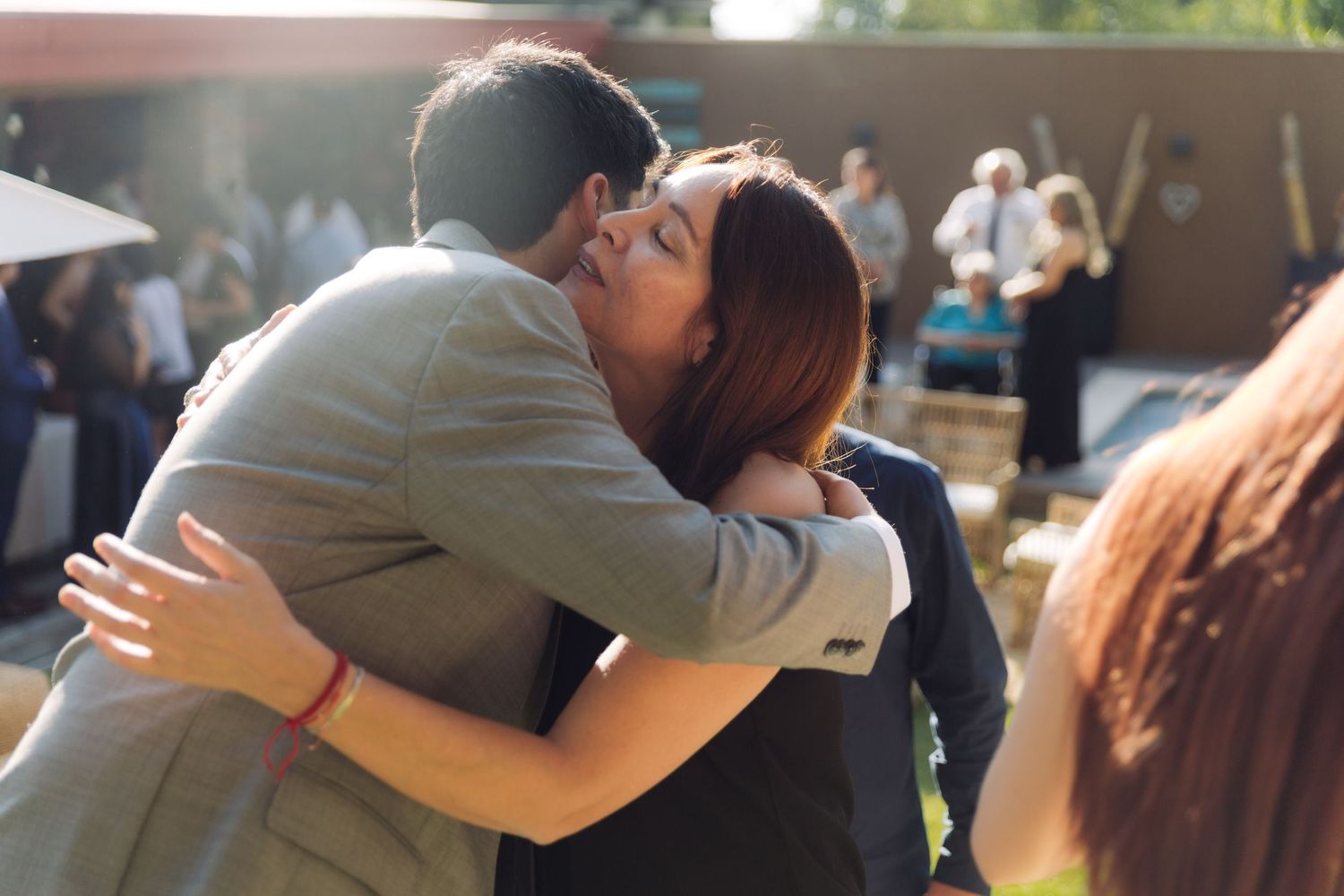 Couple sharing a close embrace at a warm sunny outdoor wedding reception.