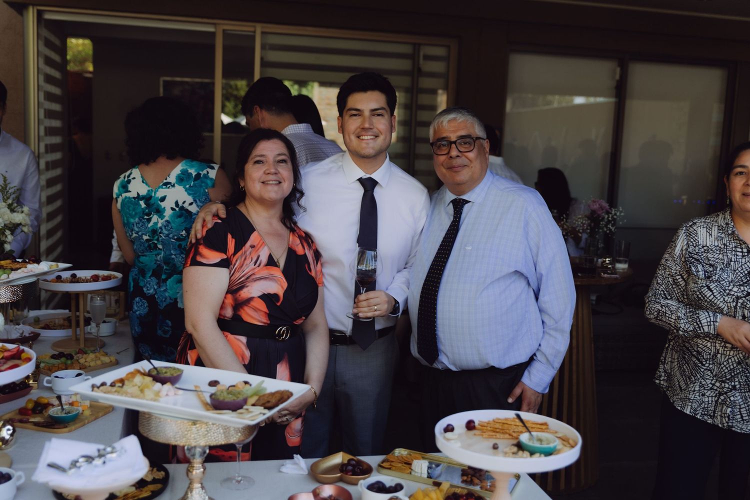 Family of three posing together at wedding reception buffet table with food displays.