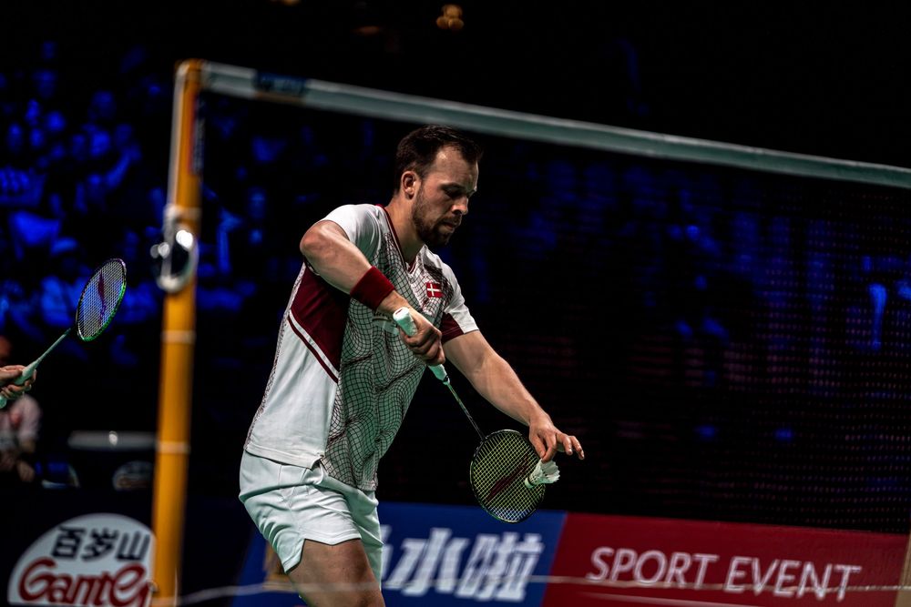 Professional badminton player mid-swing during a competitive sport event match.