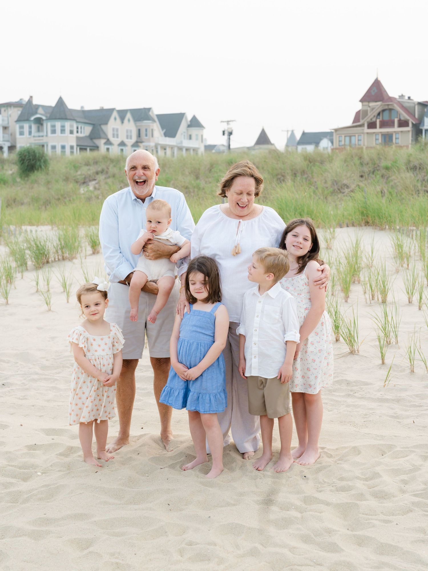 Grandparents on the beach surrounded by grandchildren during an Ocean Grove family session.