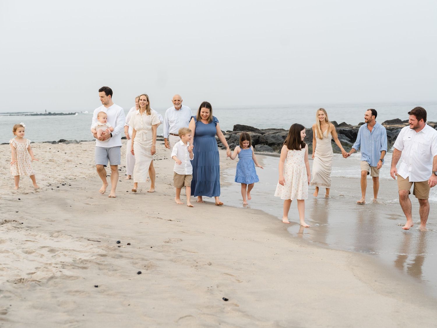 Extended family laughing naturally while walking down the shore in NJ.