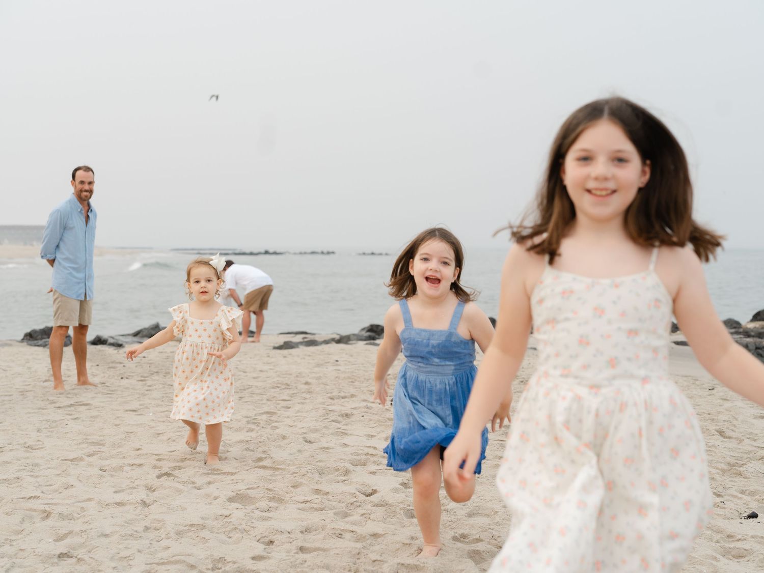 Group of young cousins running and playing along the water on monmouth county beach.