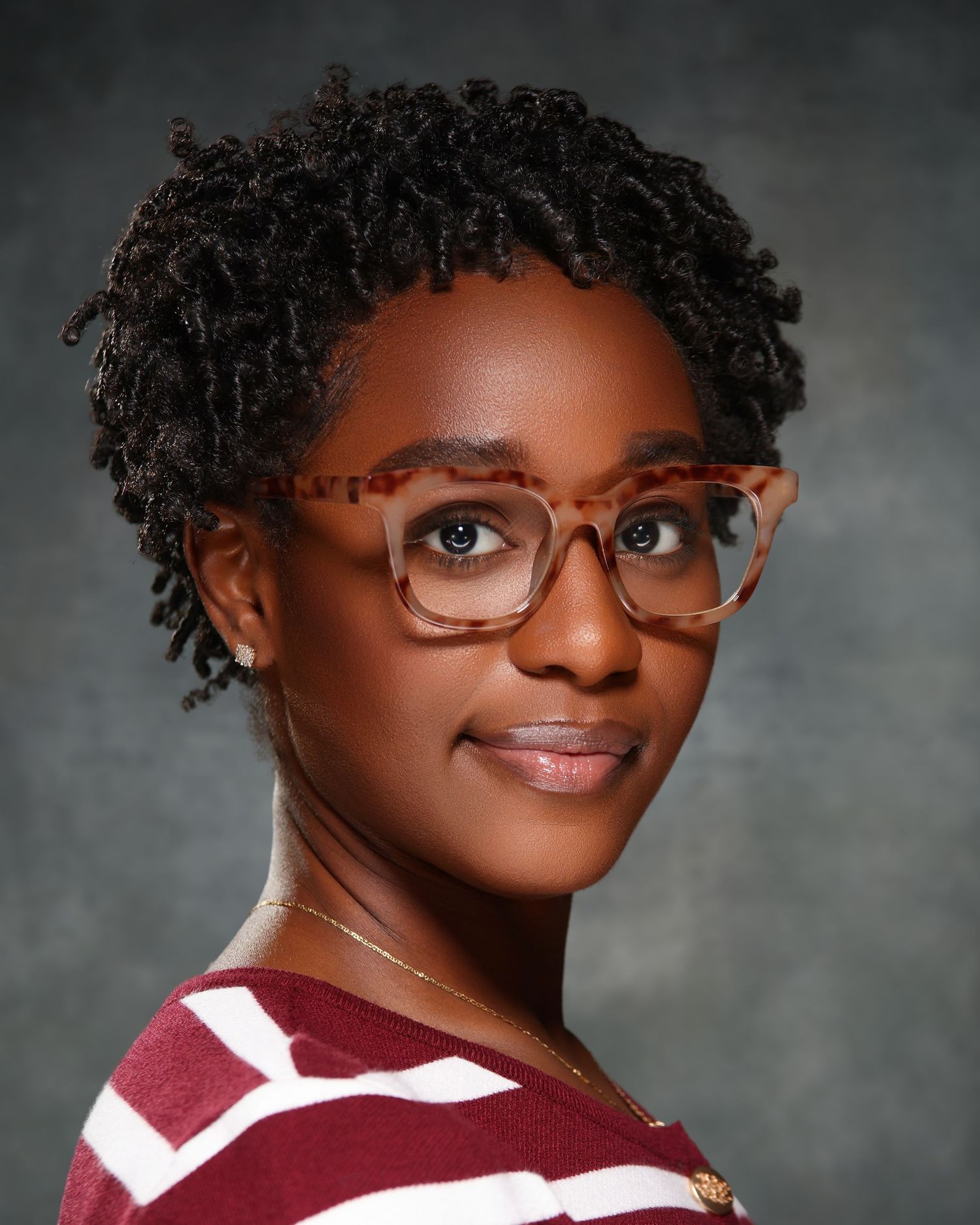 Professional headshot of a young Black woman wearing tortoiseshell glasses and a maroon striped shirt.