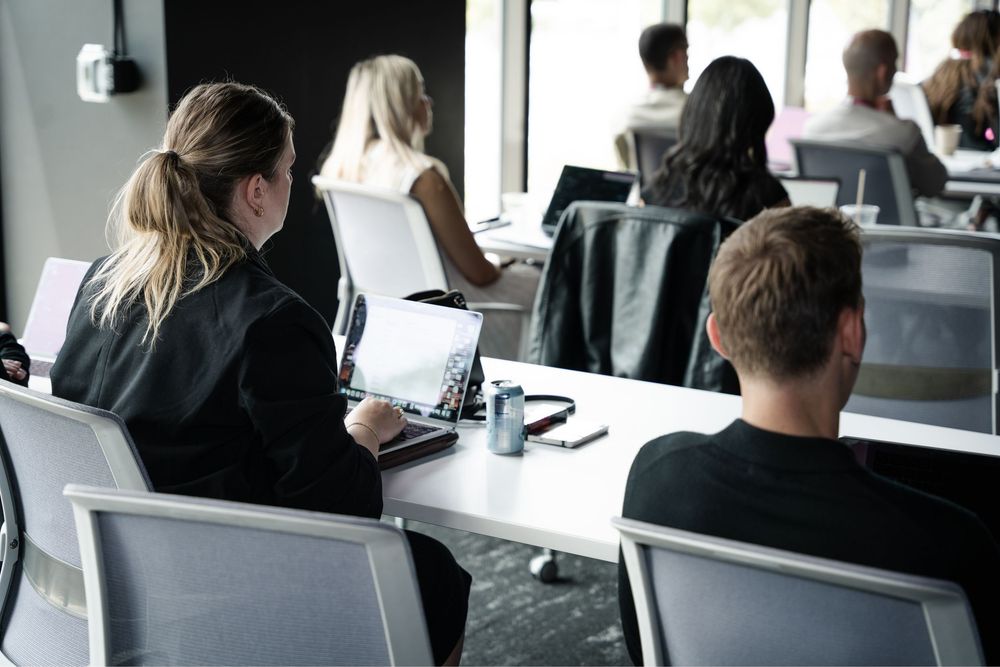 professionals working on laptops at white desks in a modern office during a business meeting or workshop.