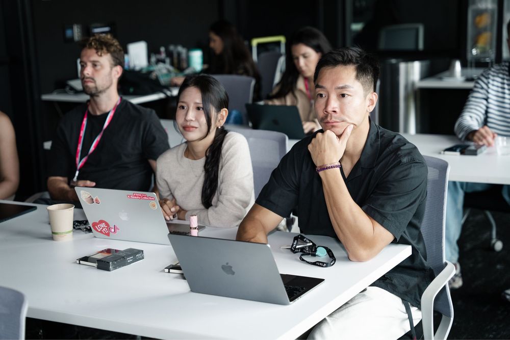 diverse group of young professionals attending a conference or workshop with laptops in a modern office.