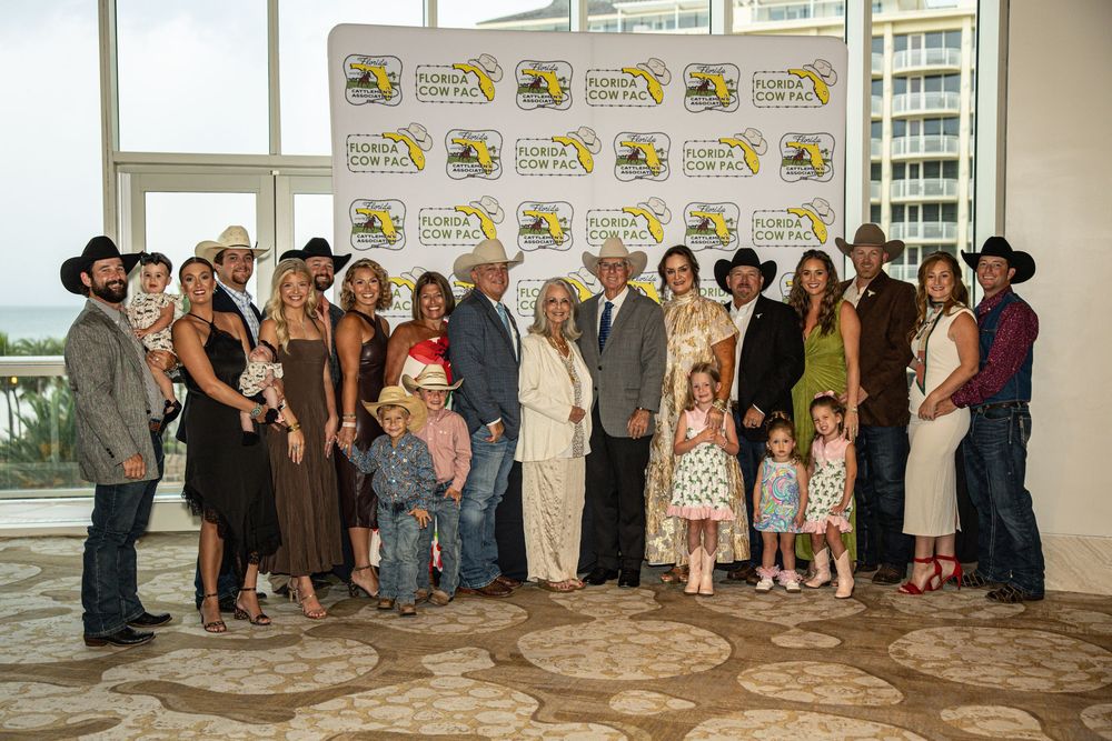 Large family group poses in formal western attire at Florida Cow Fair event backdrop in elegant venue.