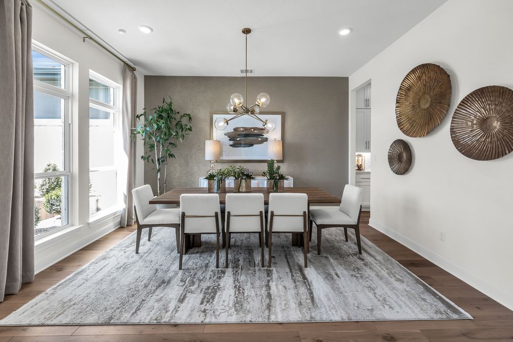 Elegant dining room with gray accent wall, chandelier, white chairs, wood floors, and decorative woven wall art.