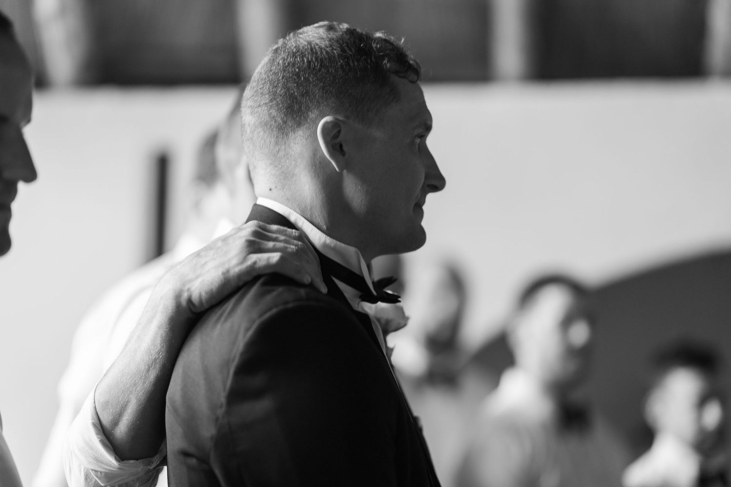 Black and white photo of two men, one with hand on other's shoulder, in a candid moment at an event.