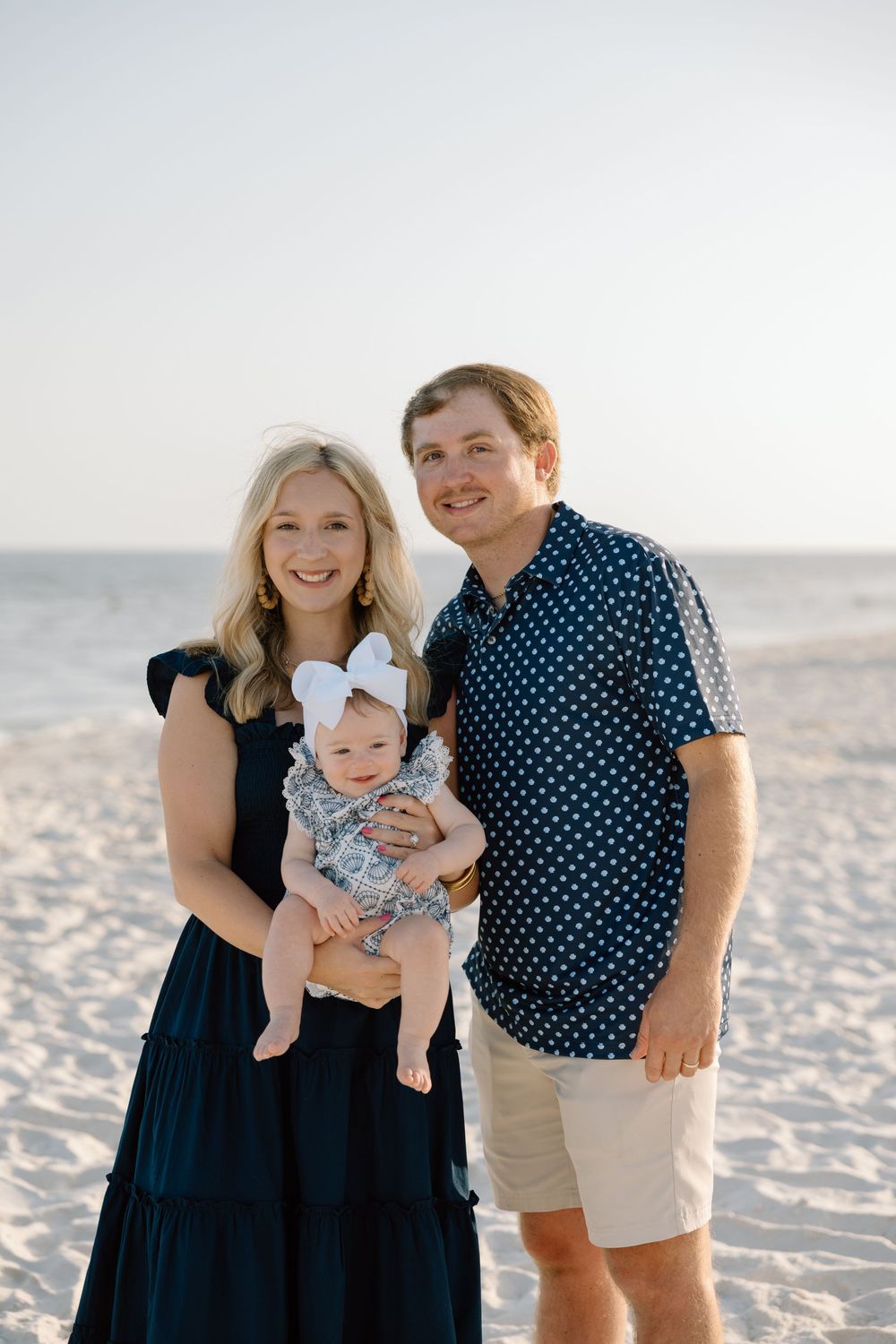 Family portrait of a couple holding their baby on the beach in Orange Beach, Alabama.