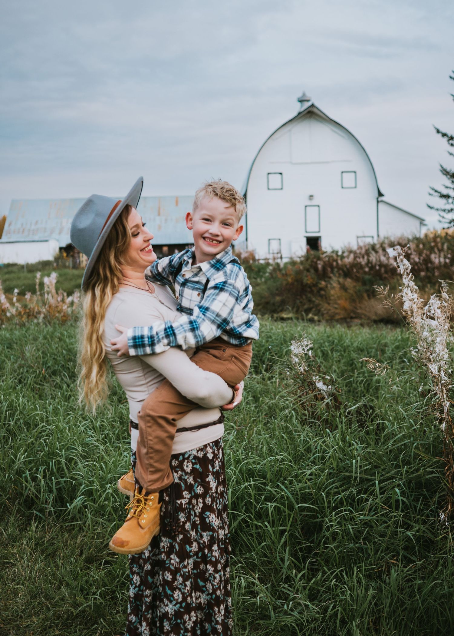 Mother holding her young child in a grassy field during an outdoor family photography session