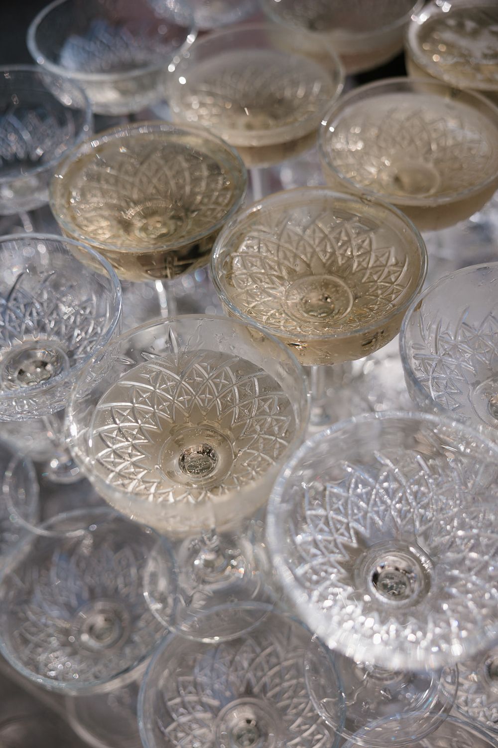 Crystal champagne coupe glasses filled with sparkling wine arranged together at an elegant event or celebration.