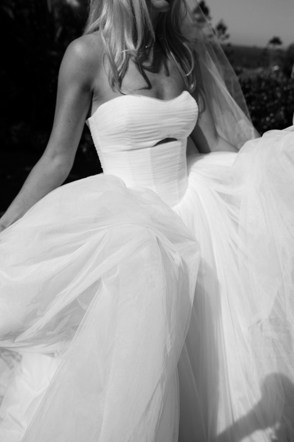 Bride in a strapless white ballgown wedding dress with flowing tulle skirt, captured in elegant black and white photography.