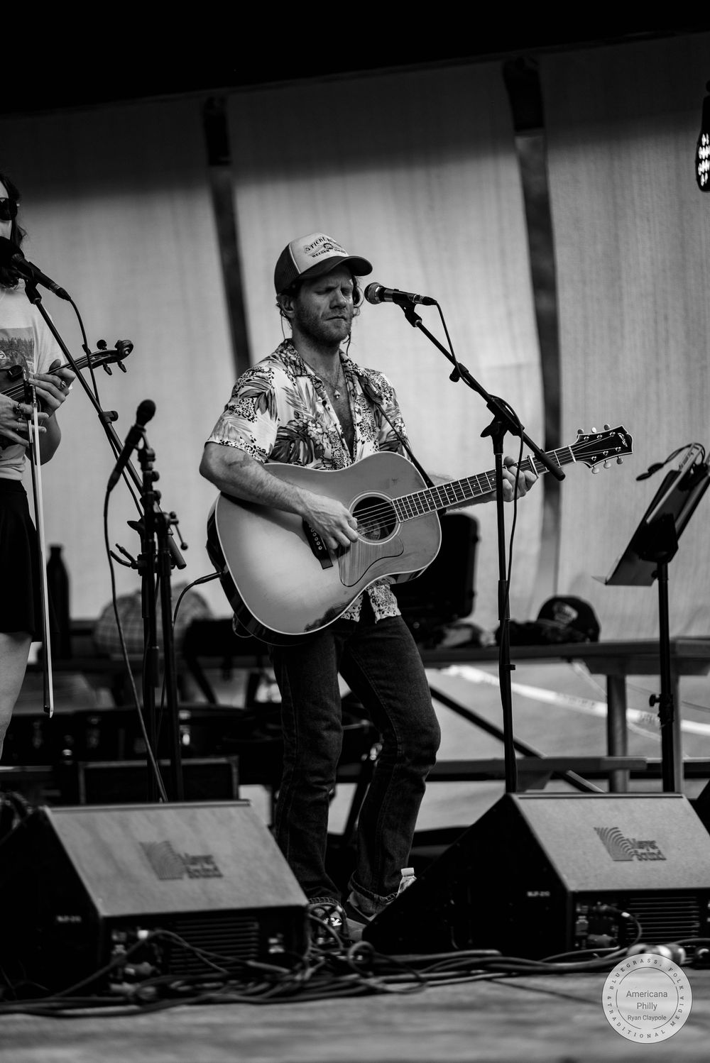 Male guitarist performing acoustic set on stage in black and white photo.