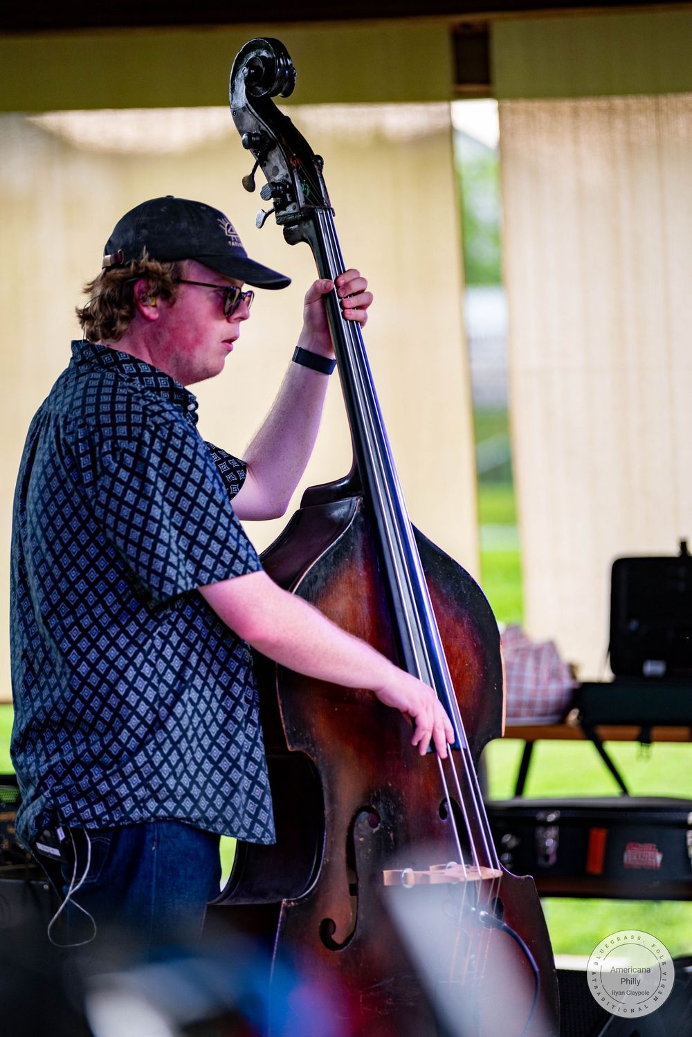 Young musician playing upright double bass outdoors at a live music festival.