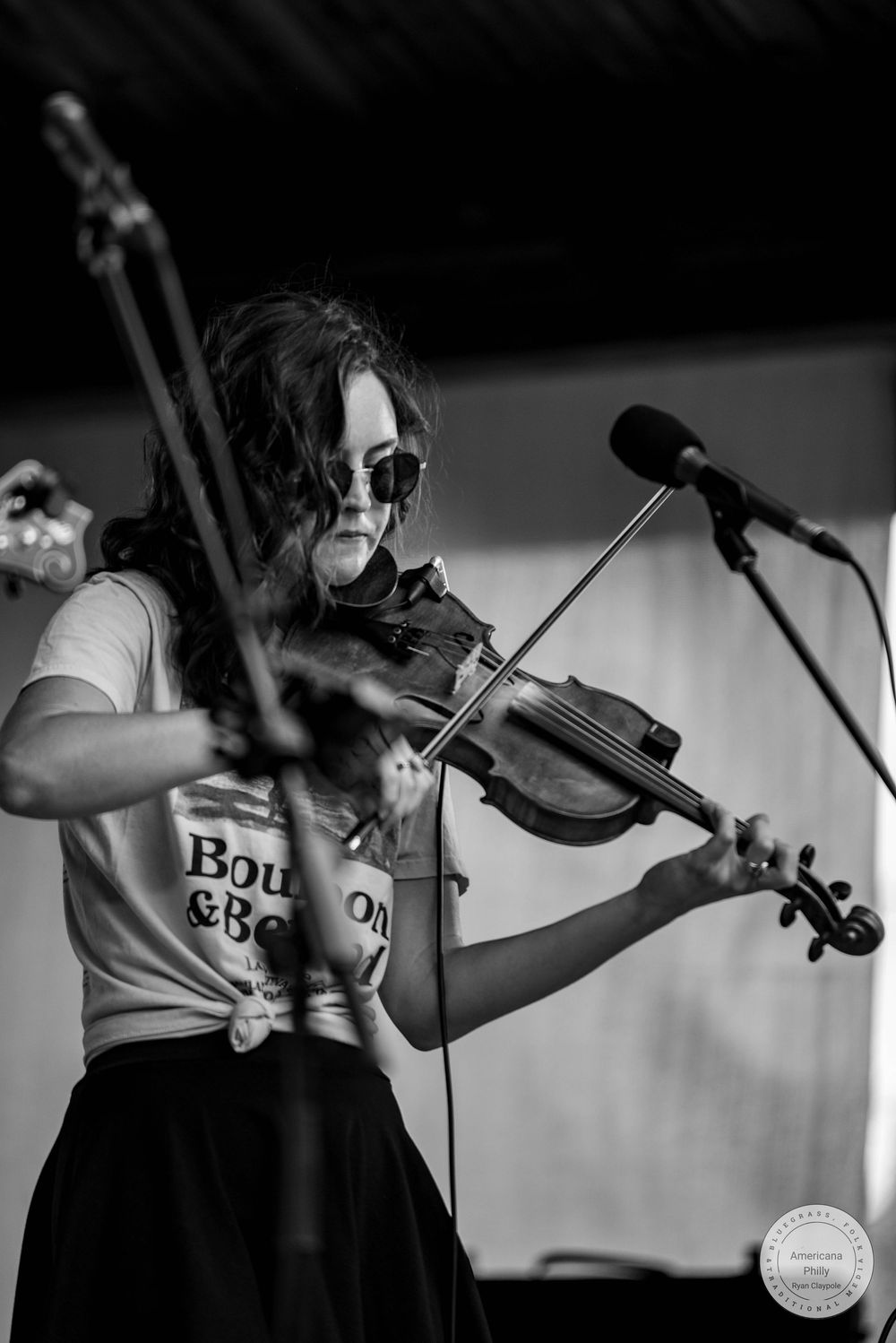 Woman playing violin on stage in black and white, wearing sunglasses and a Bourbon & Beyond t-shirt.