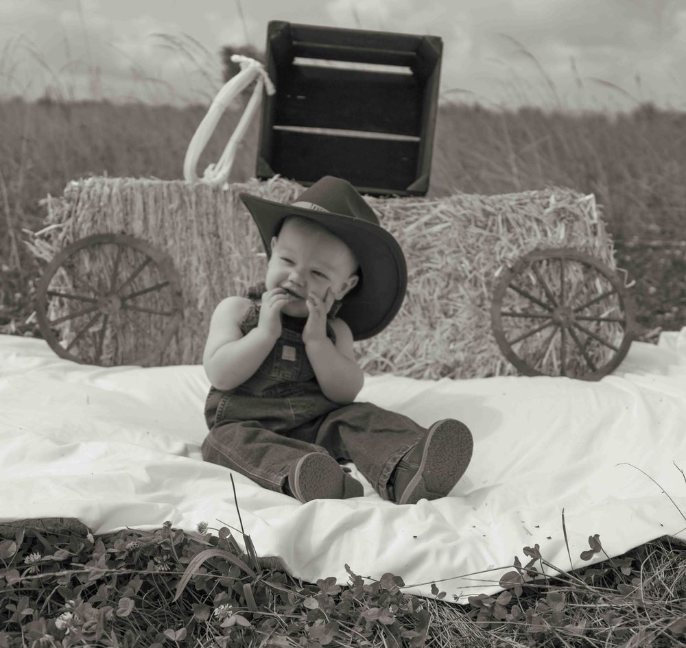 Central PA first birthday photography session featuring a little cowboy celebrating with a western-themed cake smash, cowboy hat, and boots.