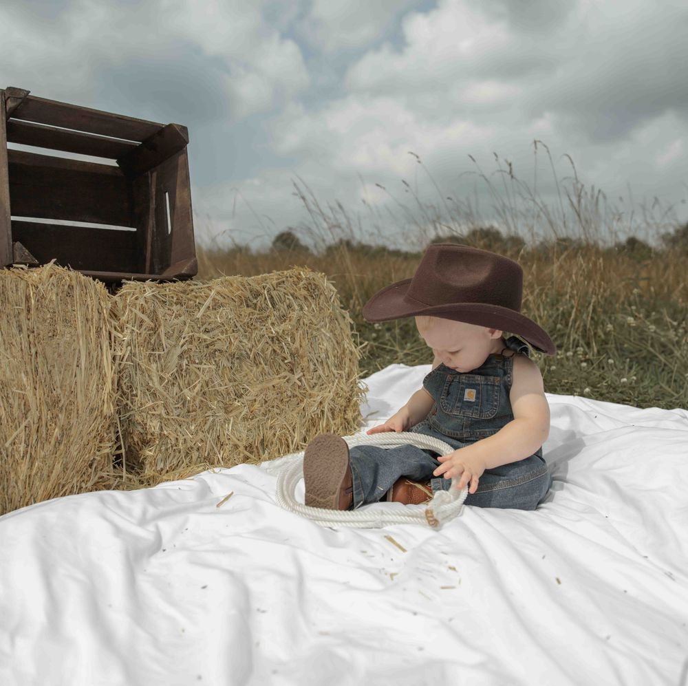 Central PA first birthday photography session featuring a little cowboy celebrating with a western-themed cake smash, cowboy hat, and boots.