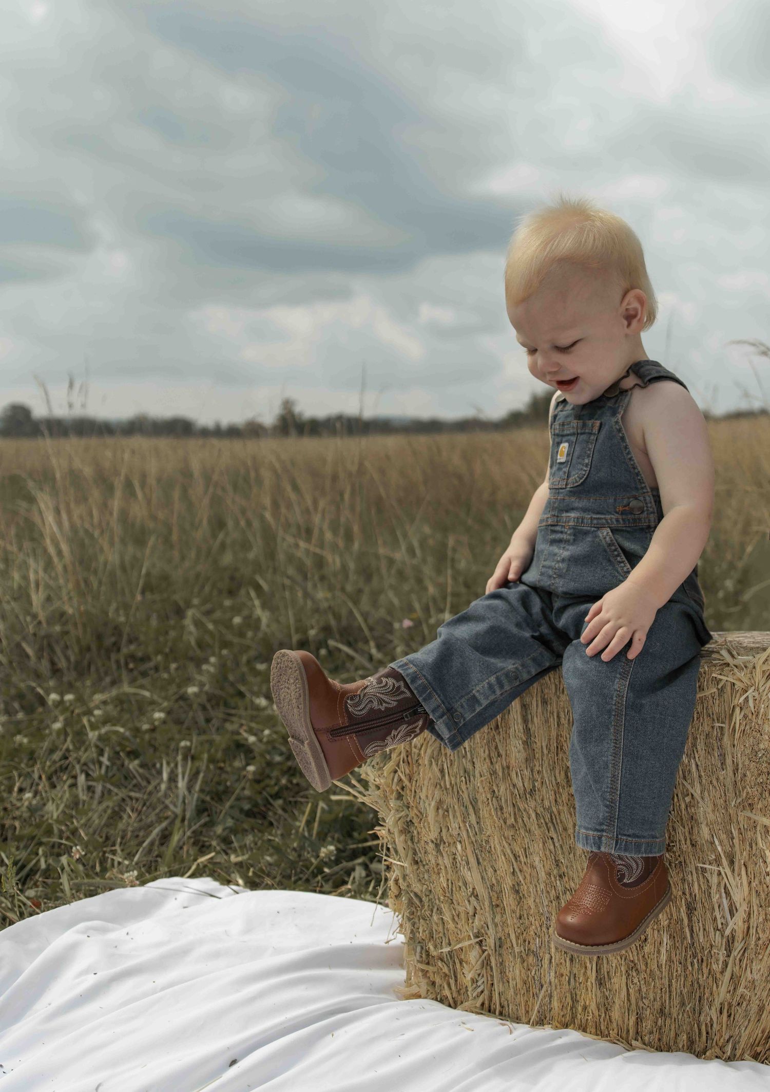 Central PA first birthday photography session featuring a little cowboy celebrating with a western-themed cake smash, cowboy hat, and boots.