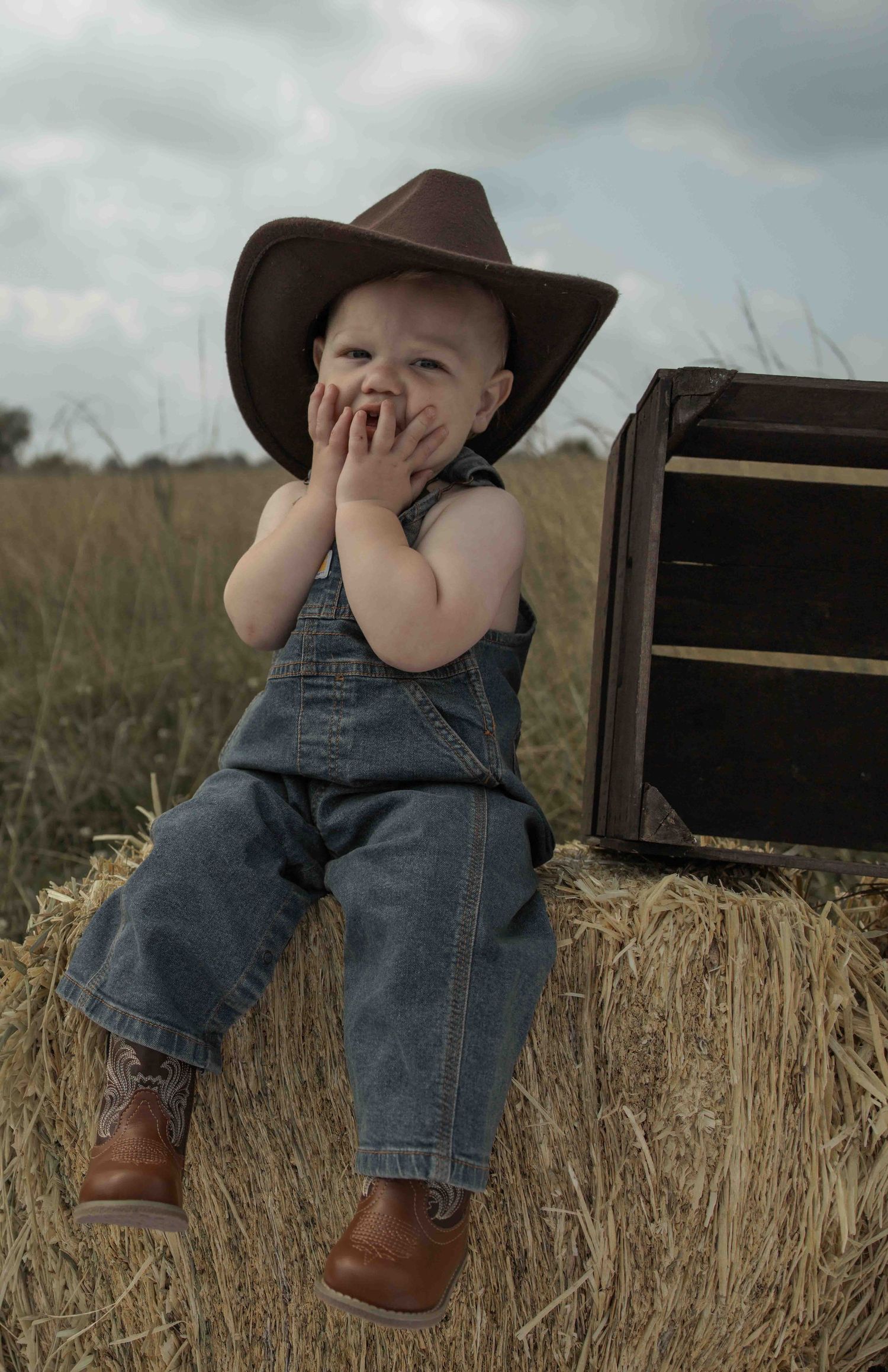 Central PA first birthday photography session featuring a little cowboy celebrating with a western-themed cake smash, cowboy hat, and boots.