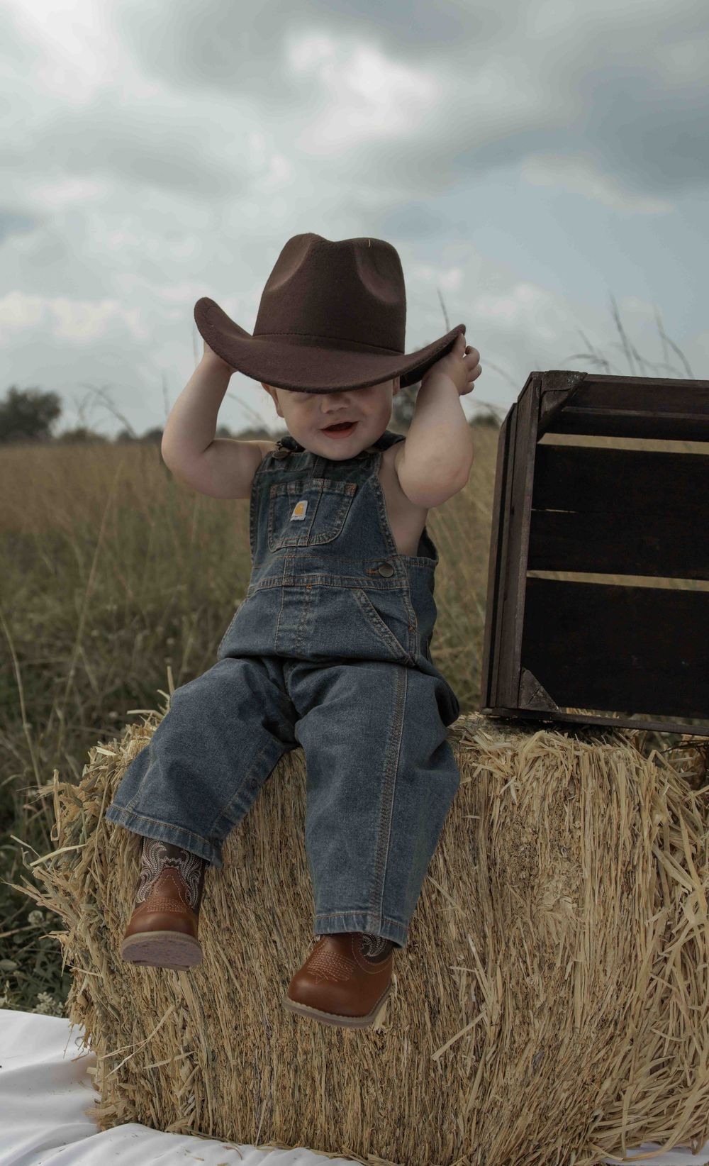 Central PA first birthday photography session featuring a little cowboy celebrating with a western-themed cake smash, cowboy hat, and boots.