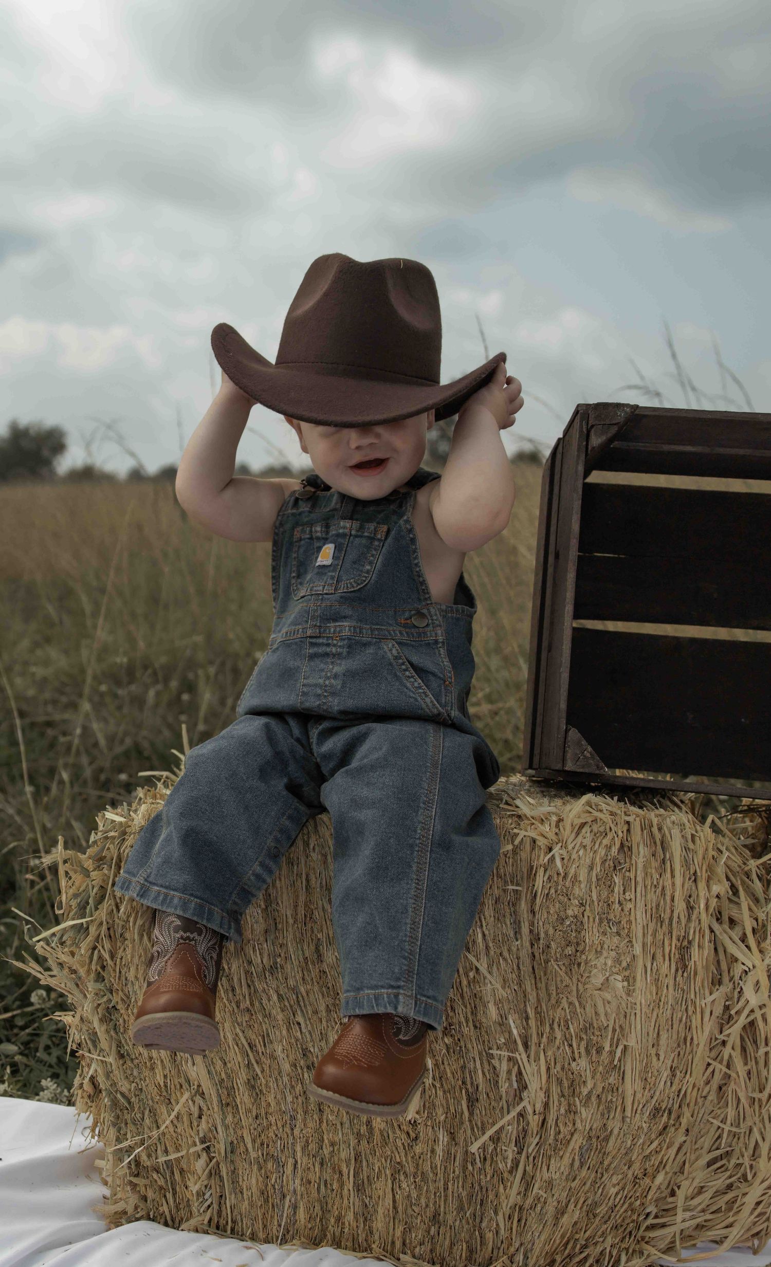 Central PA first birthday photography session featuring a little cowboy celebrating with a western-themed cake smash, cowboy hat, and boots.