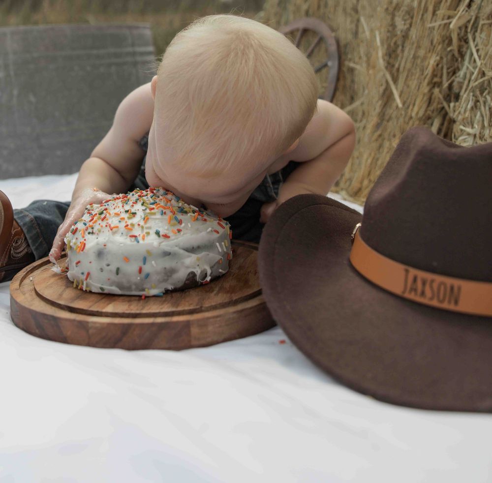 Central PA first birthday photography session featuring a little cowboy celebrating with a western-themed cake smash, cowboy hat, and boots.
