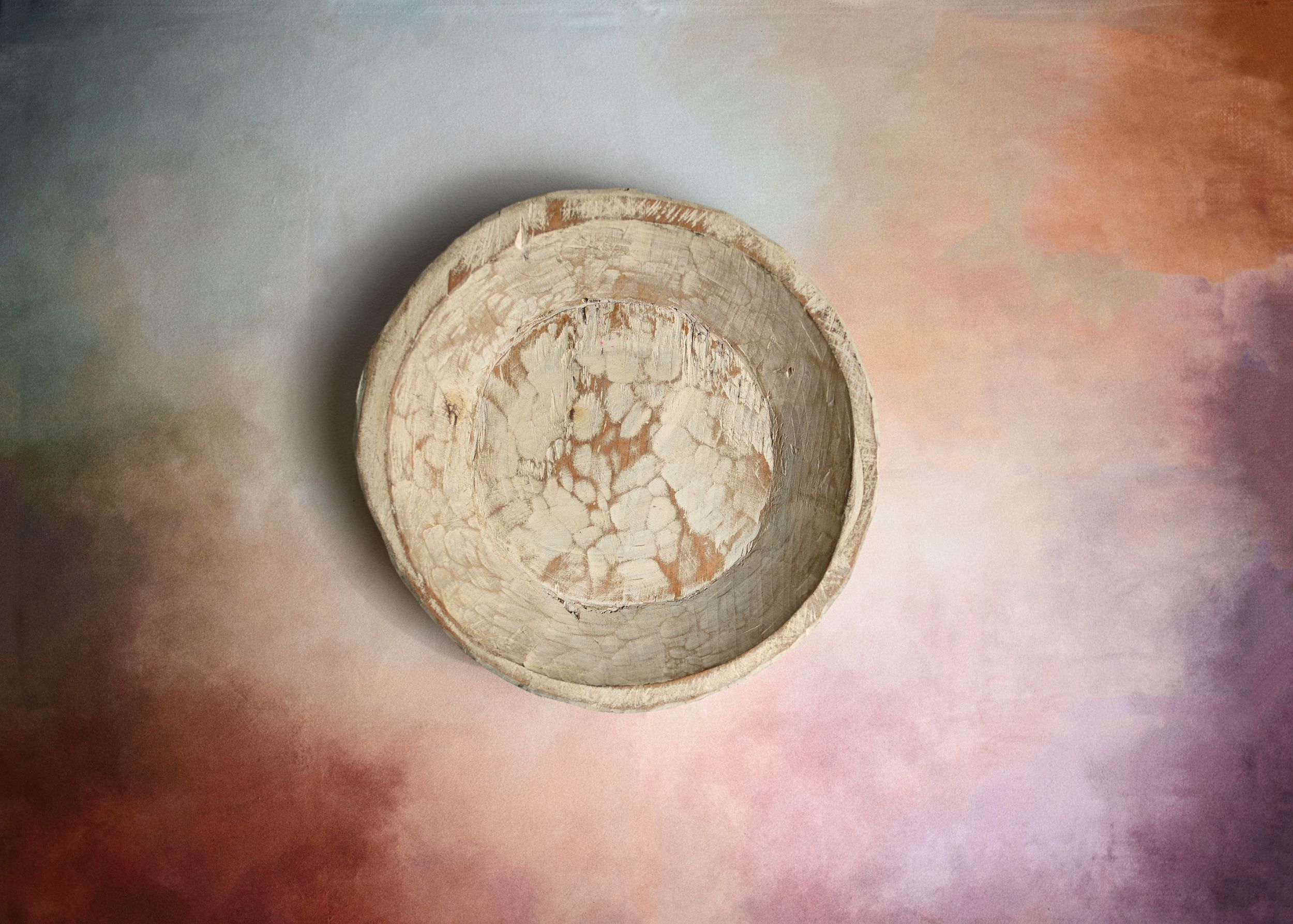 Antique ceramic bowl with marbled texture displayed against a soft pastel ombre background.