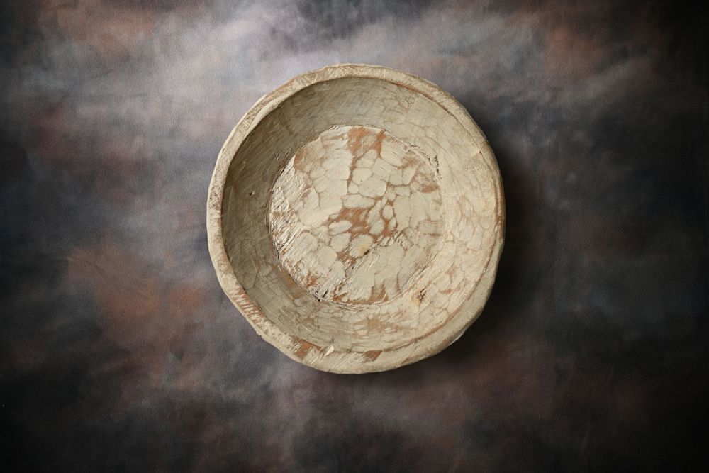 Antique ceramic bowl with crackled glaze pattern, photographed from above on dark textured background.