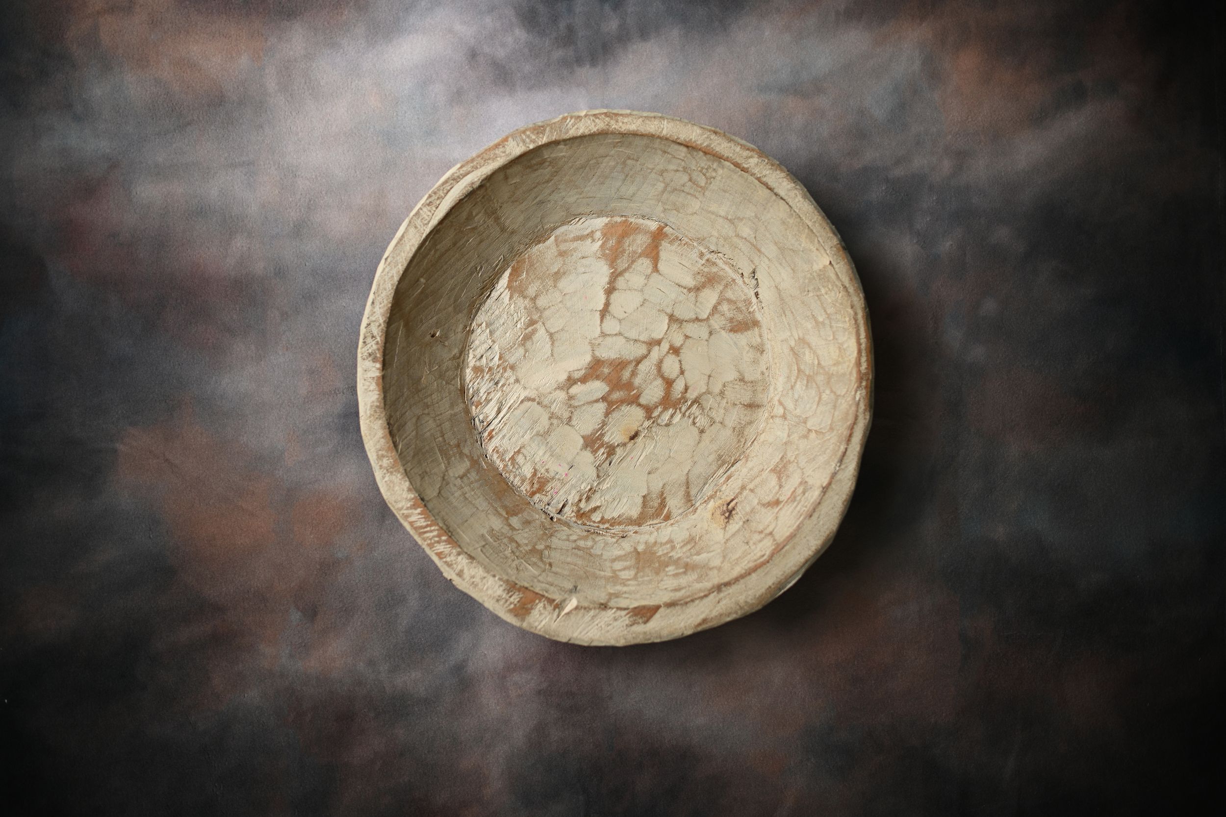 Antique ceramic bowl with crackled glaze pattern, photographed from above on dark textured background.