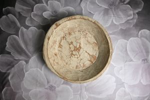 Rustic handmade ceramic bowl with marble-like pattern on floral background.