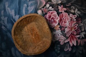 Rustic wooden bowl on a dark floral fabric background with pink and mauve flowers.