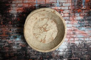 Rustic handmade ceramic bowl with marbled texture displayed against a weathered brick wall backdrop.