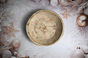 A rustic marble-patterned bowl surrounded by festive Christmas decorations, snowflakes, and rose gold ornaments on white background.
