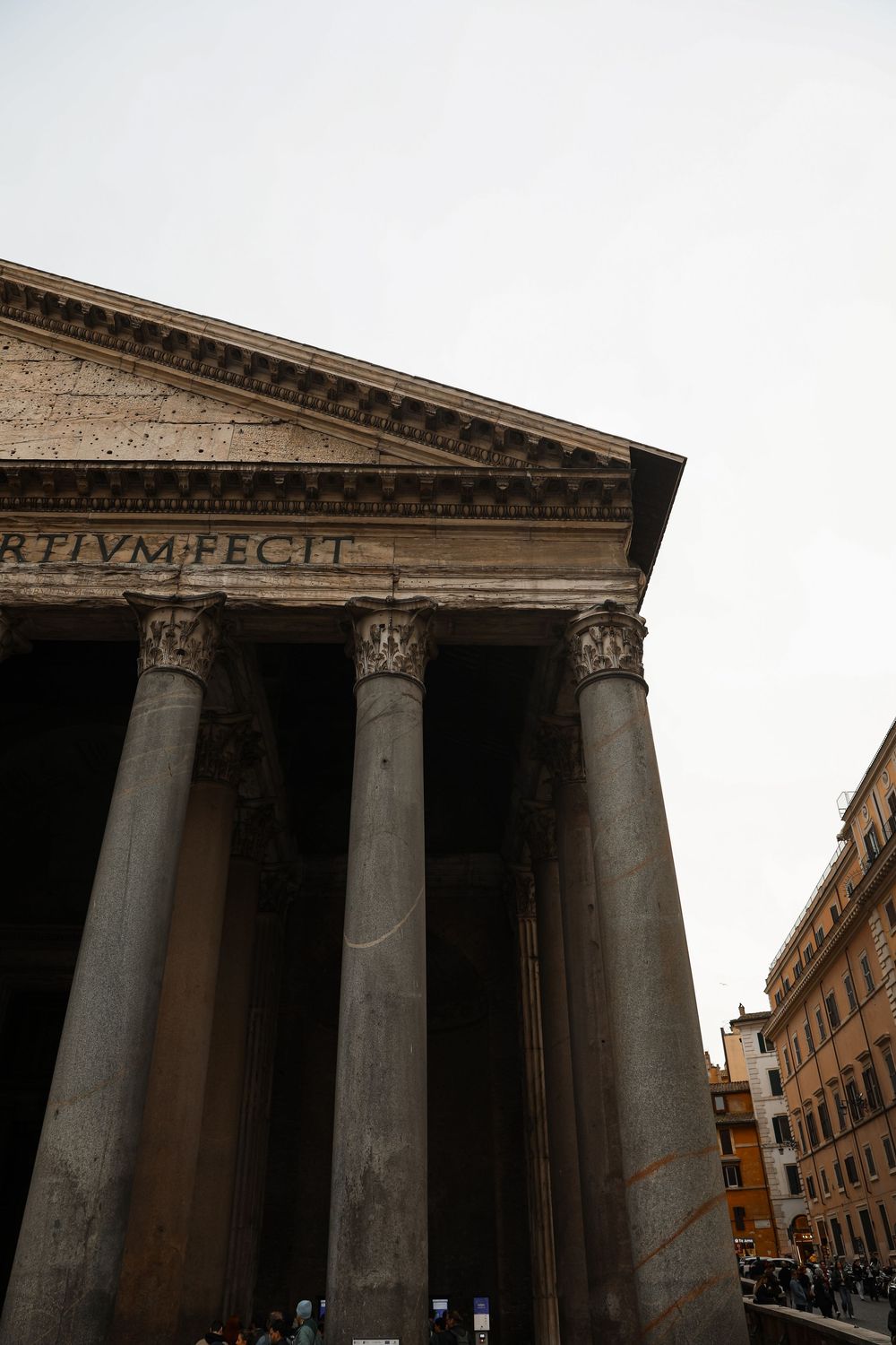 Ancient Roman Pantheon facade with towering Corinthian columns and Latin inscription under overcast sky in Rome, Italy.