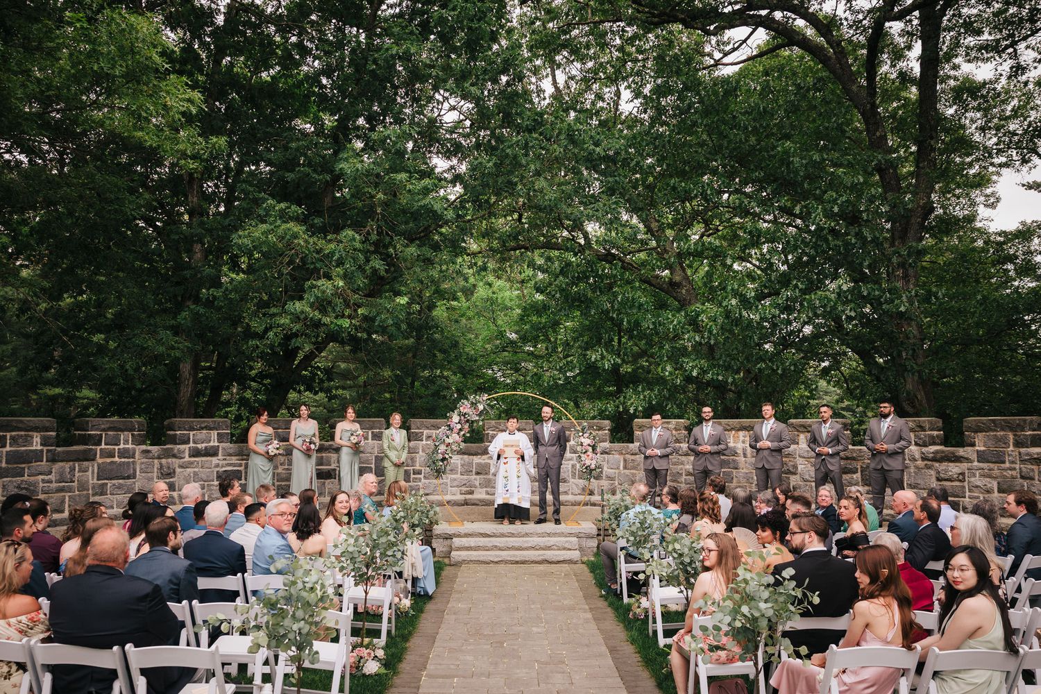 Wedding party lined up along a stone wall at Searles Castle, waiting for the bride to arrive at the ceremony.