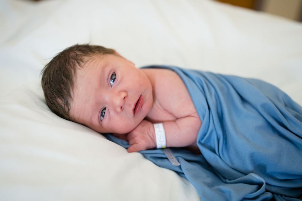Newborn baby wrapped in blue swaddle blanket during a Fresh 48 Session at Fort Sanders in Knoxville, TN.