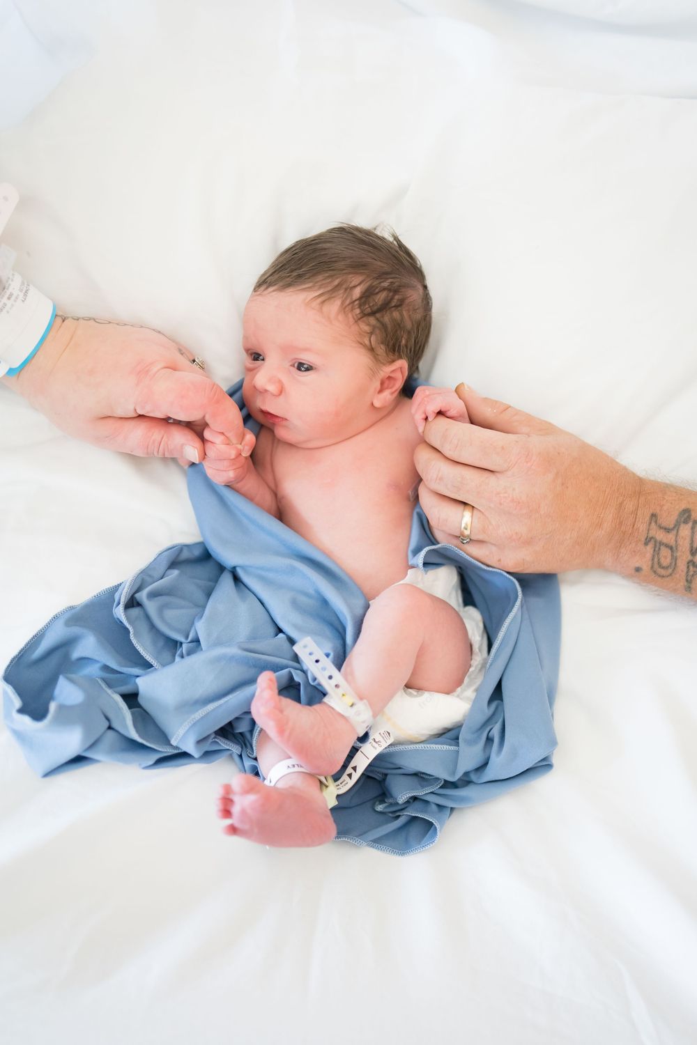 Newborn baby lying on white blanket with hospital bracelet during a Fresh 48 Session at Fort Sanders in Knoxville, TN.