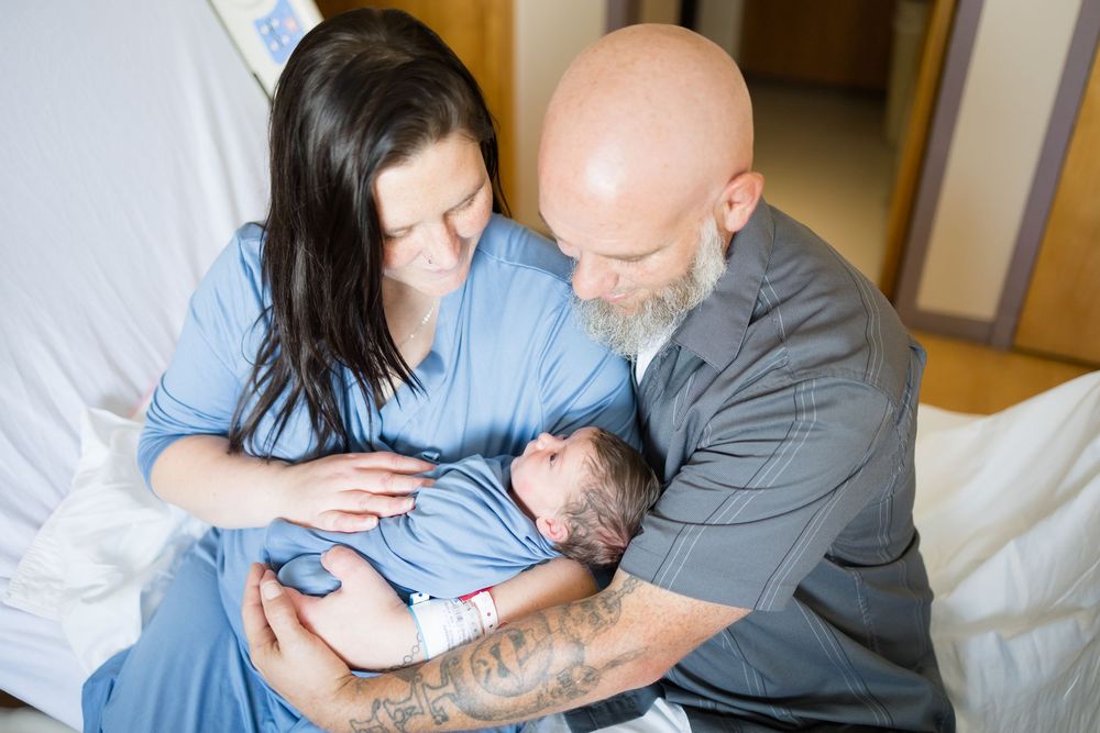 New parents holding their newborn baby in hospital room during a Fresh 48 Session at Fort Sanders in Knoxville, TN.