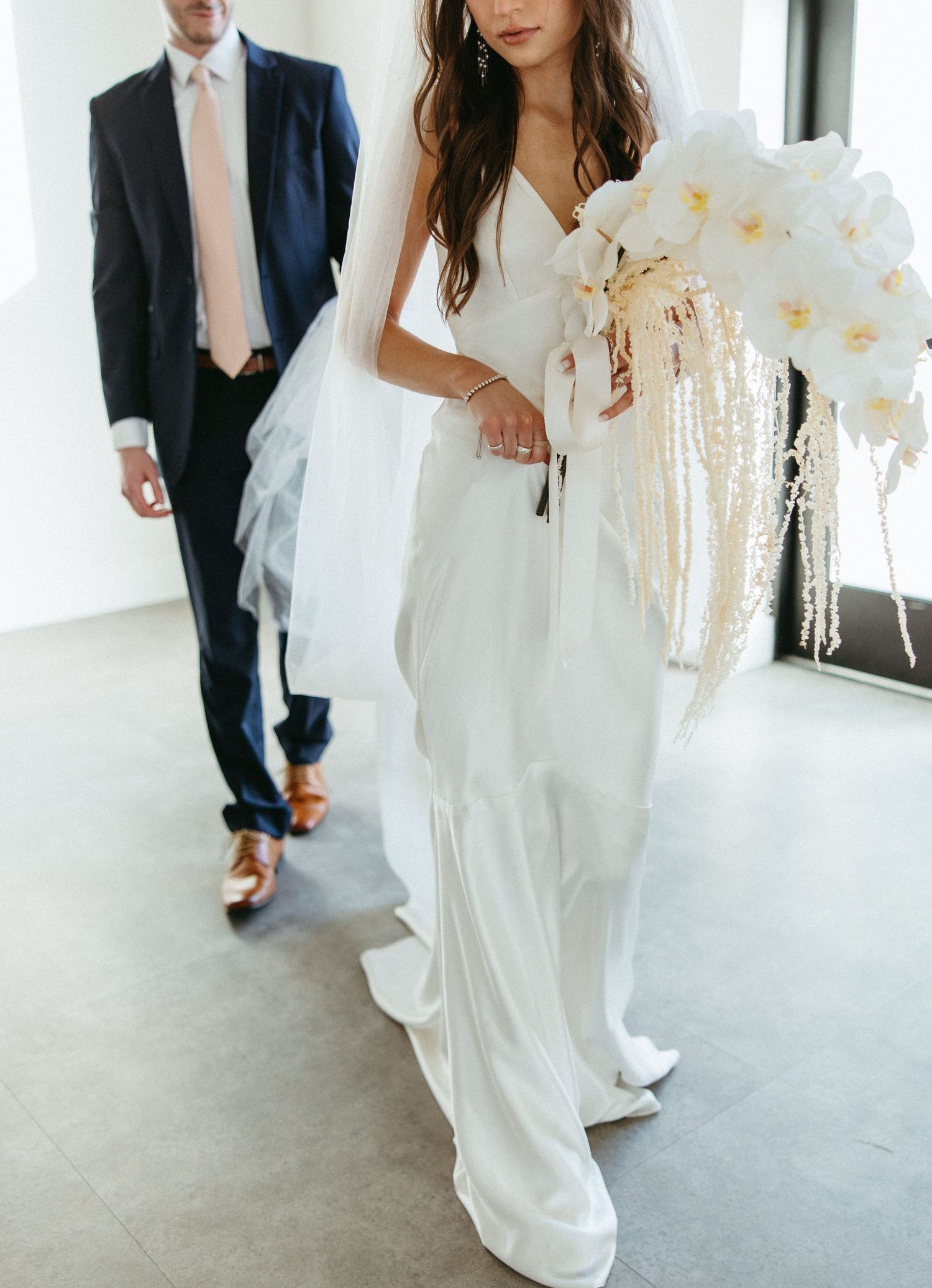 Elegant wedding dress details and movement captured in a bright white venue.