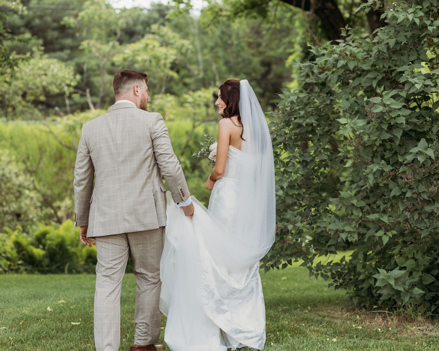 couple walking together back to venue at barn at loon cove in skowhegan maine after having there portrait photos done by wedding photographe