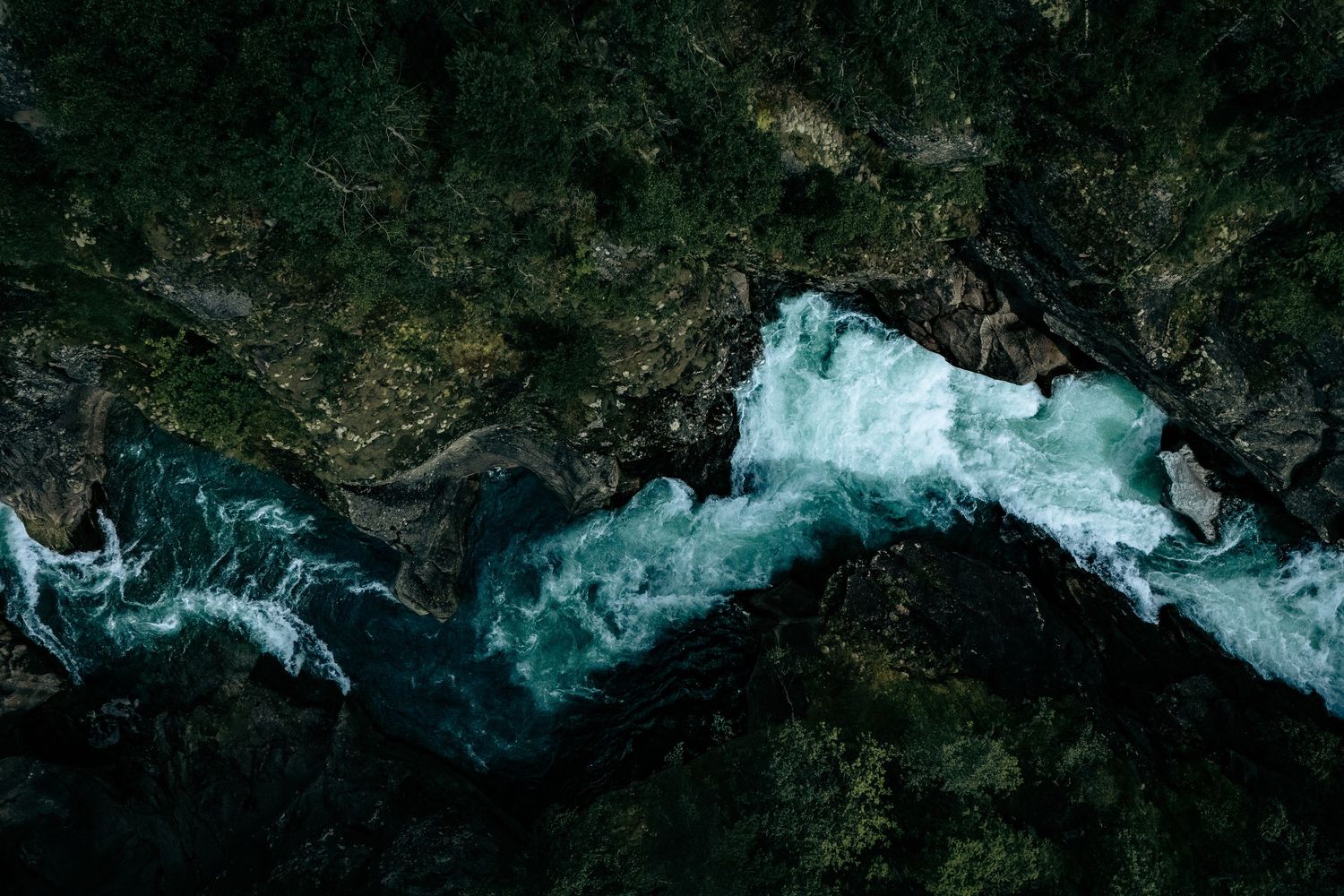 Dronefotografi af brusende vand mellem mørke klipper – dramatisk naturfotografi som fotokunst og kunstprint.